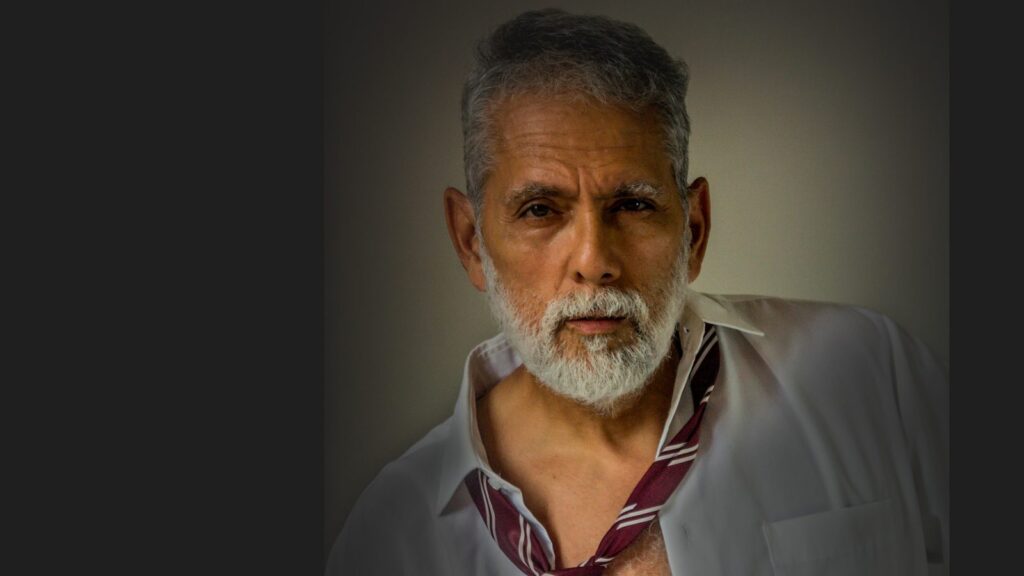 Men’s Sex Drive Peaks at 40. Testosterone Isn’t Why. A silver-bearded man in mid-life with a loosened tie and open collar, meeting the camera with a confident look, against a dark background.